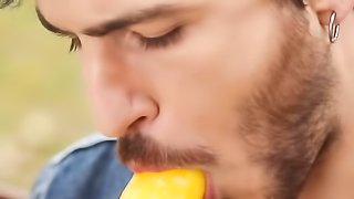 Cute bearded dude licks a dick shaped lollipop in an open area near the bridge