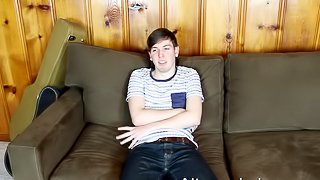 Gay guy with short dark hair playing with his huge cock on his sofa